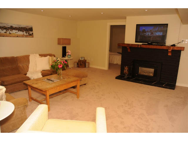 Furnished living room with beige carpet, fireplace, and large window. - Suite-942 Belvedere Drive, North Vancouver