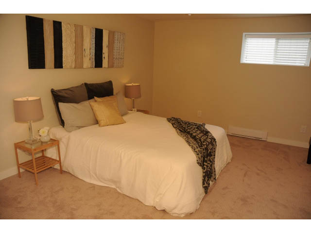 Spacious bedroom with twin beds, neutral decor, and a small nightstand. - Suite-942 Belvedere Drive, North Vancouver