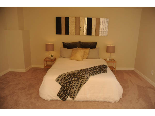 Spacious bedroom with neutral tones, plush carpet, and modern artwork above the bed. - Suite-942 Belvedere Drive, North Vancouver