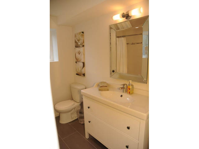 Bright bathroom with white vanity and countertop, framed artwork on wall. - Suite-942 Belvedere Drive, North Vancouver