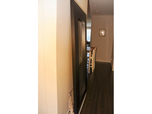 Bright hallway leading to living area with hardwood floors and a framed artwork on the wall. - 306-215 East 33rd Ave, Vancouver East Side