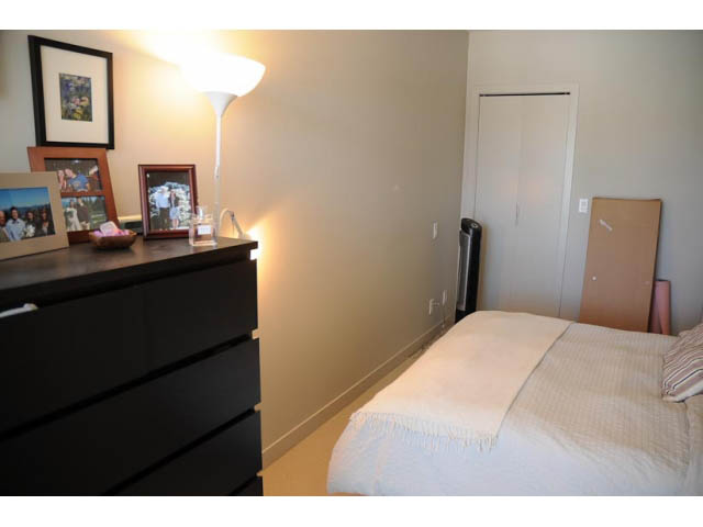 Furnished 1-bedroom bedroom with a black dresser, white bedding, and a tall floor lamp. - 306-215 East 33rd Ave, Vancouver East Side