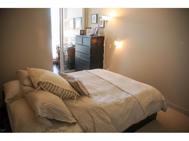 Furnished 1-bedroom with cozy bed, soft lighting, and dresser in the corner. - 306-215 East 33rd Ave, Vancouver East Side