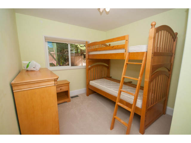 Bright bedroom with bunk beds, wooden furniture, and a window view. - 2704 Sechelt Drive, North Vancouver