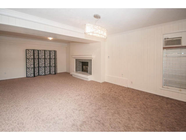 Spacious living room with fireplace, chandelier, and large windows. - Suite- 3897 St. Pauls Ave, North Vancouver