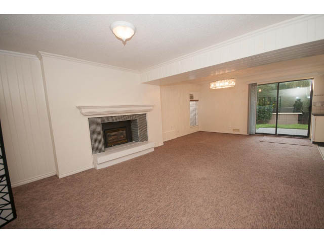 Spacious living room with fireplace and large sliding glass door leading to outdoor patio. - Suite- 3897 St. Pauls Ave, North Vancouver