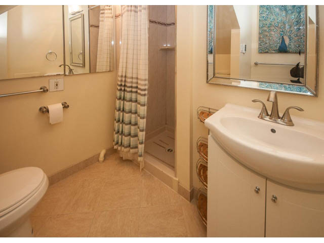 Furnished bathroom with beige walls, wooden vanity, and large mirror. - Suite- 3897 St. Pauls Ave, North Vancouver