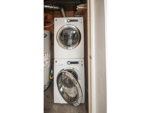 Laundry room with stacked washer and dryer, utility area visible. - Suite- 3897 St. Pauls Ave, North Vancouver
