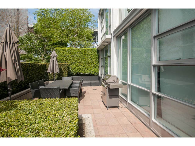 Furnished patio with outdoor furniture and greenery, modern glass windows. - 106 - 633 Kinghorne Mews, Vancouver Downtown