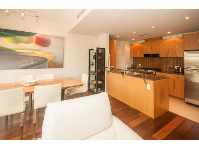 Bright kitchen with wooden cabinets, hardwood floors, and a modern dining area. - 106 - 633 Kinghorne Mews, Vancouver Downtown
