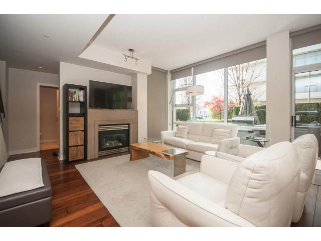Spacious living room with white leather sofas, hardwood floors, and a city view. - 106 - 633 Kinghorne Mews, Vancouver Downtown