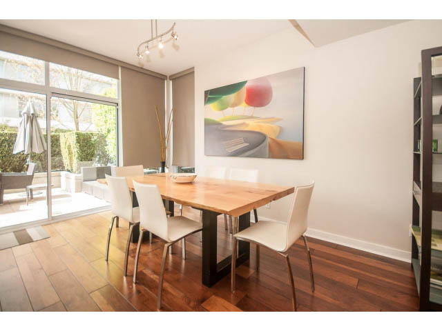 Furnished dining area with hardwood floors, modern artwork, and sliding glass doors leading to a patio. - 106 - 633 Kinghorne Mews, Vancouver Downtown