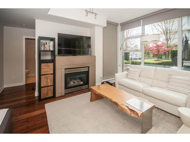 Spacious living room with modern fireplace, hardwood floors, and city view. - 106 - 633 Kinghorne Mews, Vancouver Downtown
