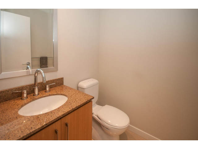 Bright bathroom with granite countertops and a white toilet. - 106 - 633 Kinghorne Mews, Vancouver Downtown