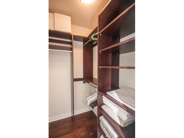 Furnished walk-in closet with wooden shelves and hanging space. - 106 - 633 Kinghorne Mews, Vancouver Downtown