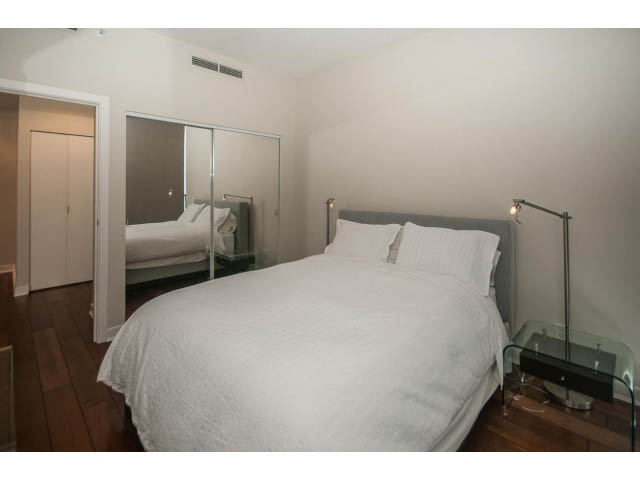 Furnished bedroom with hardwood floors and a mirrored closet. - 106 - 633 Kinghorne Mews, Vancouver Downtown