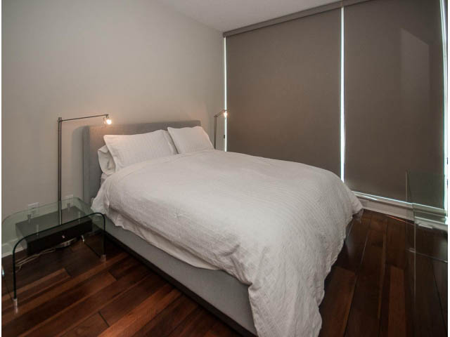 Furnished bedroom with hardwood floors and modern sliding blinds. - 106 - 633 Kinghorne Mews, Vancouver Downtown