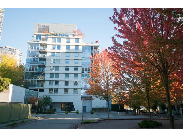 Furnished living room with large windows, city view, and autumn trees. - 106 - 633 Kinghorne Mews, Vancouver Downtown