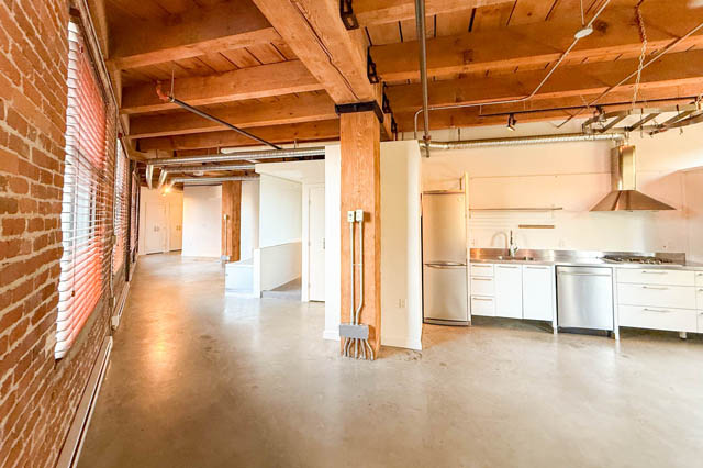 Open loft kitchen with concrete countertops and exposed brick wall. - 221 - 55 E. Cordova, Vancouver Downtown