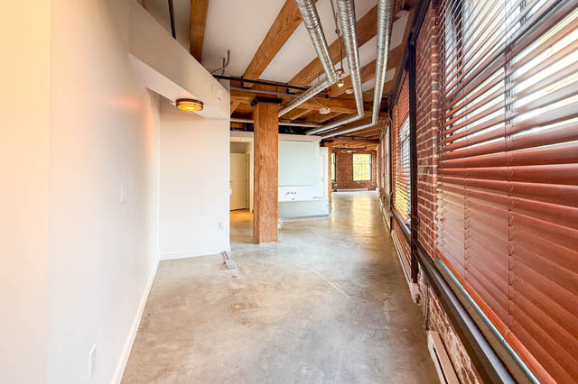 Spacious loft with concrete floors, exposed wooden beams, and brick walls, perfect for a cozy downtown living space.