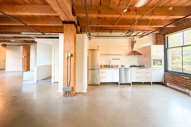 Open loft kitchen with concrete floors, white cabinets, and stainless steel appliances. - 221 - 55 E. Cordova, Vancouver Downtown