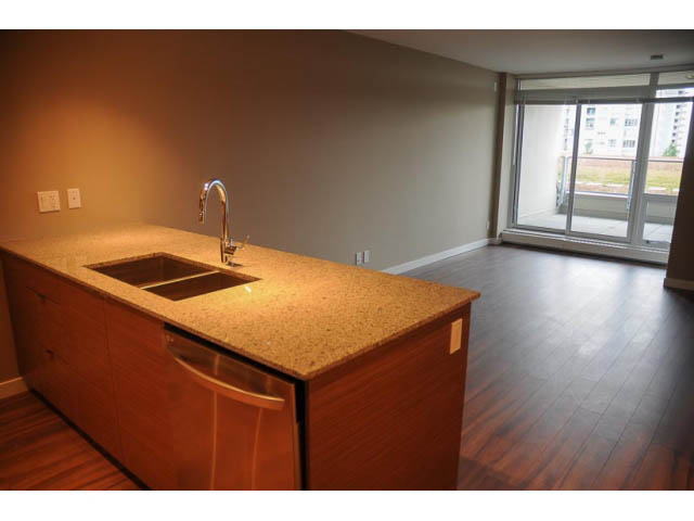 Bright kitchen with granite countertops and hardwood floors, featuring a city view. - 310 - 135 East 17th Street, North Vancouver