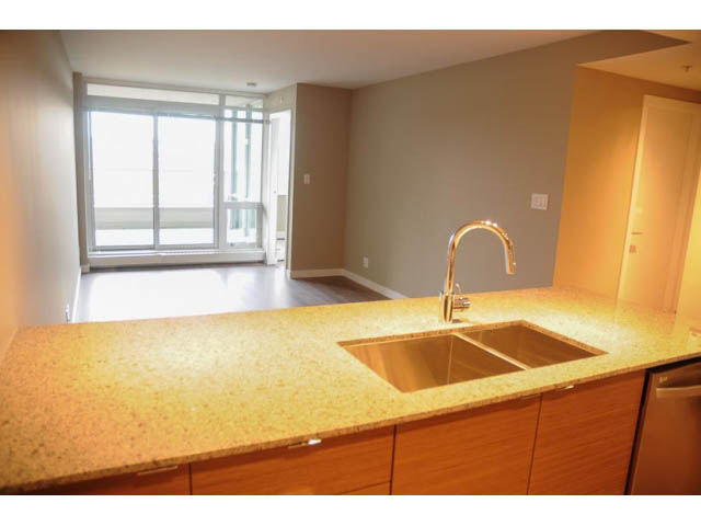 Bright kitchen with granite countertops and modern faucet, leading to a spacious balcony with city view. - 310 - 135 East 17th Street, North Vancouver