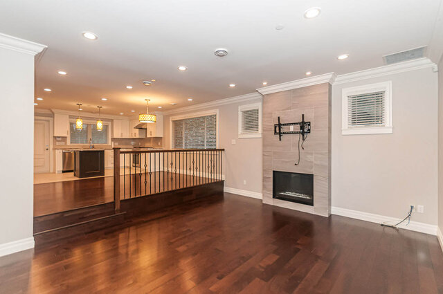 Open-concept living room with hardwood floors and a modern fireplace, showcasing a spacious and inviting atmosphere.
