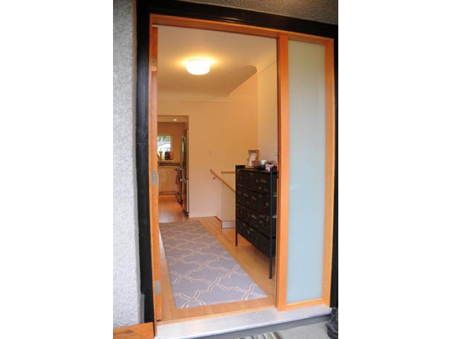 Furnished living room with hardwood floors and sliding glass doors leading to a patio. - 1362 East 20th St, North Vancouver