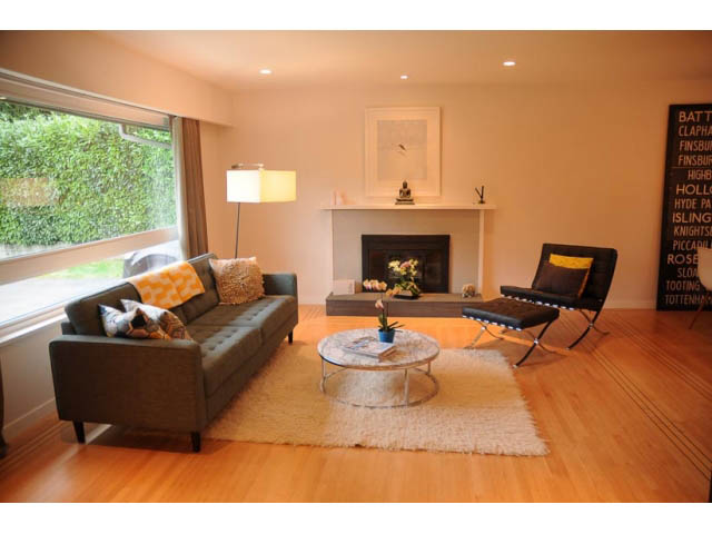 Spacious living room with hardwood floors, modern furniture, and a large window. - 1362 East 20th St, North Vancouver