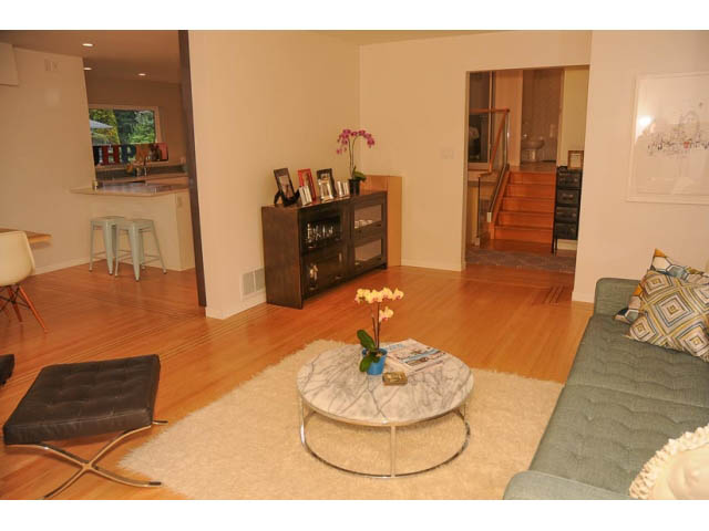 Bright living room with hardwood floors, modern furniture, and a city view. - 1362 East 20th St, North Vancouver