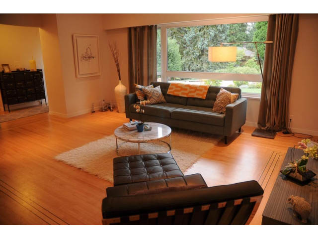 Furnished living room with hardwood floors, modern furniture, and large windows. - 1362 East 20th St, North Vancouver