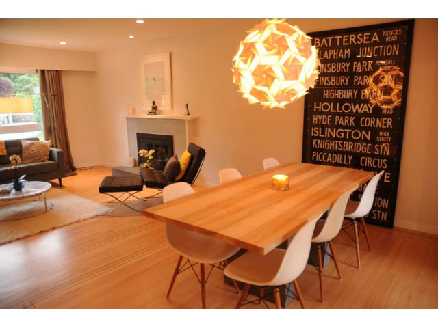 Furnished dining area with wooden table, modern chairs, and city-themed wall art. - 1362 East 20th St, North Vancouver