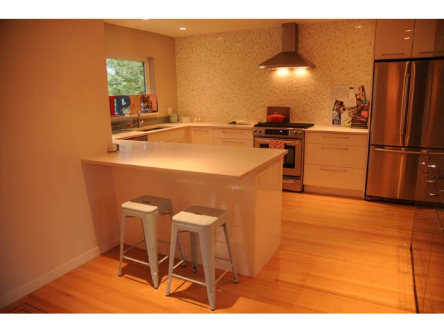 Bright kitchen with white countertops, hardwood floors, and a city view. - 1362 East 20th St, North Vancouver