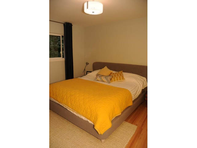 Furnished bedroom with hardwood floors and a cozy yellow quilt. - 1362 East 20th St, North Vancouver