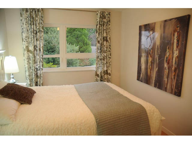 Spacious bedroom with large window, cozy bedding, and abstract wall art. - 1362 East 20th St, North Vancouver