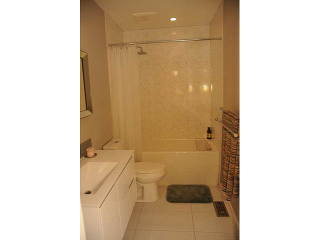 Furnished bathroom with white cabinets, tiled walls, and a shower curtain. - 1362 East 20th St, North Vancouver