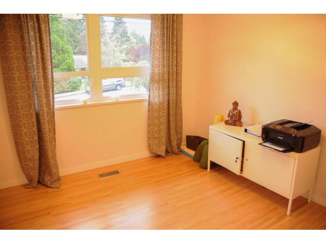 Bright living room with hardwood floors, large windows, and a view of greenery outside. - 1362 East 20th St, North Vancouver