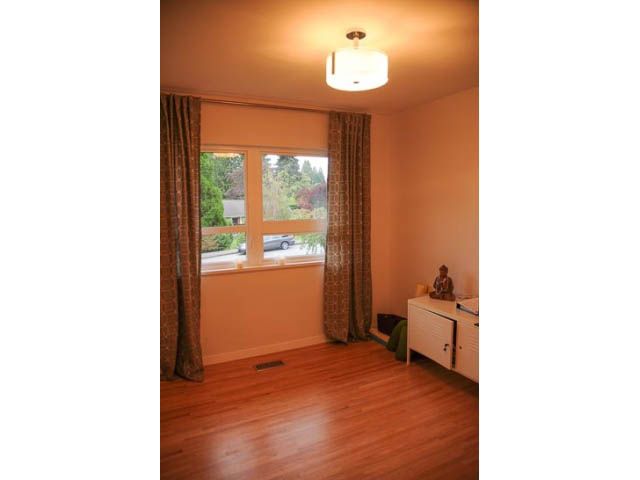 Spacious living room with hardwood floors and large windows offering a city view. - 1362 East 20th St, North Vancouver