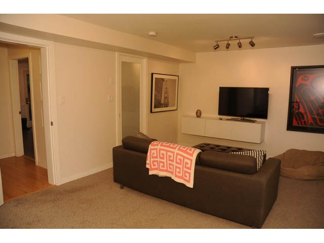 Furnished living room with modern furniture, artwork, and a flat-screen TV. - 1362 East 20th St, North Vancouver