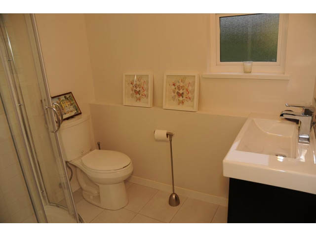 Bright bathroom with white fixtures, countertop, and framed artwork on the wall. - 1362 East 20th St, North Vancouver