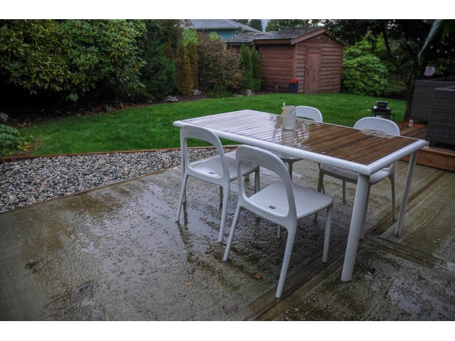 Furnished patio with wet concrete and white plastic furniture. - 1362 East 20th St, North Vancouver