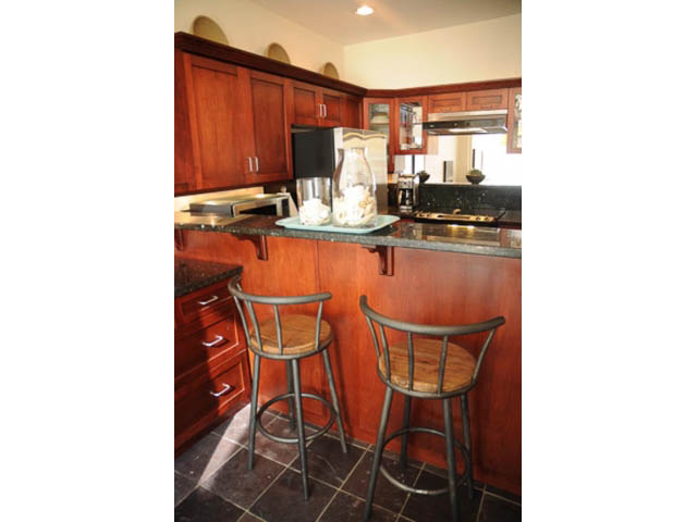 Bright kitchen with dark granite countertops and wooden bar stools, modern appliances. - 121 -1228 Marinaside Crescent, Vancouver Downtown