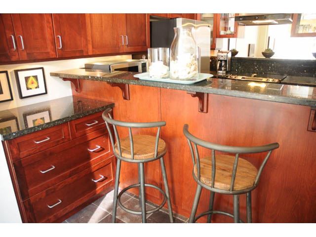 Bright kitchen with dark granite countertops and wooden bar stools, showcasing a modern design. - 121 -1228 Marinaside Crescent, Vancouver Downtown