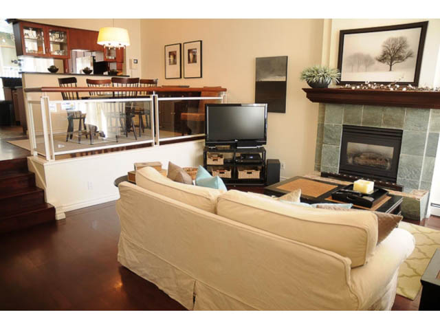 Furnished living room with hardwood floors, modern fireplace, and dining area in the background. - 121 -1228 Marinaside Crescent, Vancouver Downtown