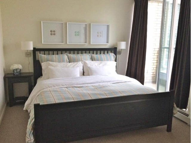 Furnished bedroom with striped bedding and large windows. - 121 -1228 Marinaside Crescent, Vancouver Downtown
