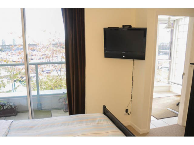 Bright bedroom with city view and mounted TV. - 121 -1228 Marinaside Crescent, Vancouver Downtown