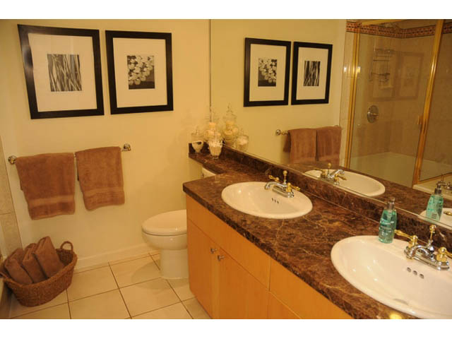 Furnished bathroom with dark marble countertops and wooden cabinets. - 121 -1228 Marinaside Crescent, Vancouver Downtown