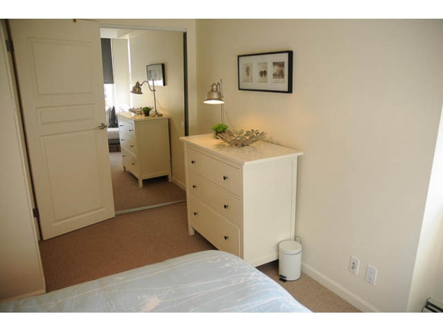 Furnished bedroom with white walls, built-in storage, and a small trash bin. - 121 -1228 Marinaside Crescent, Vancouver Downtown