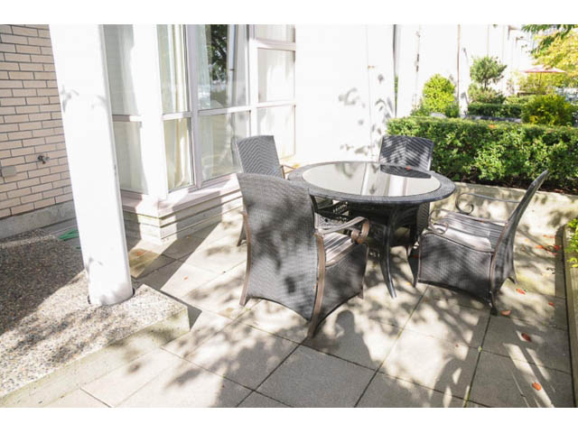 Furnished patio with outdoor table and chairs, surrounded by greenery and sunlight. - 121 -1228 Marinaside Crescent, Vancouver Downtown
